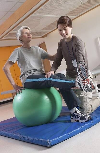 Orlando PTA helping elderly patient regain mobility on exercise ball