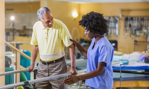 Physical therapist assistant helping patient regain balance while walking 