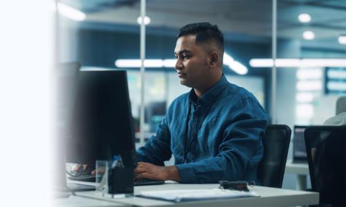 Software Developer Seated at Computer Desk In Office 