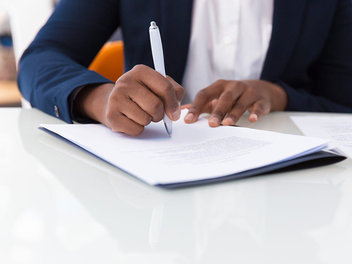 Paralegal Seated at Desk Taking Notes During Meeting