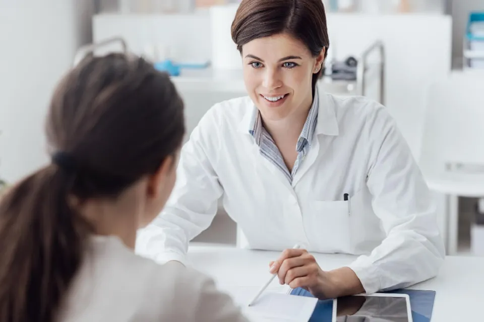 Adult-Gerontology Nurse Practitioner (AGNP) discussing treatment plan with patient and smiling