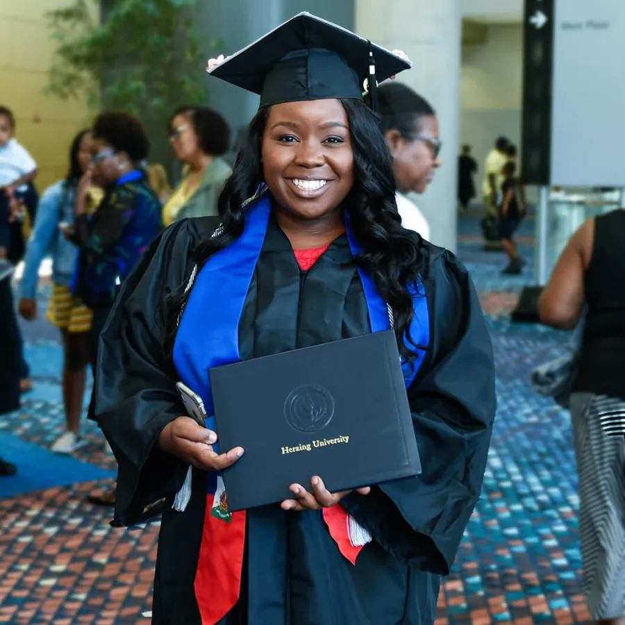 Herzing University Graduate Holding Diploma and Smiling