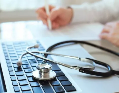 HIM Student Taking Notes in Front of Laptop with Stethoscope