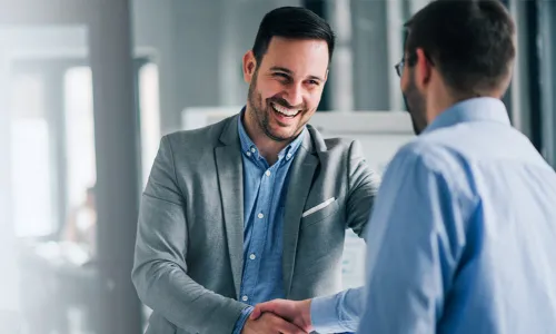 MBA graduate smiling and shaking hands after earning leadership position